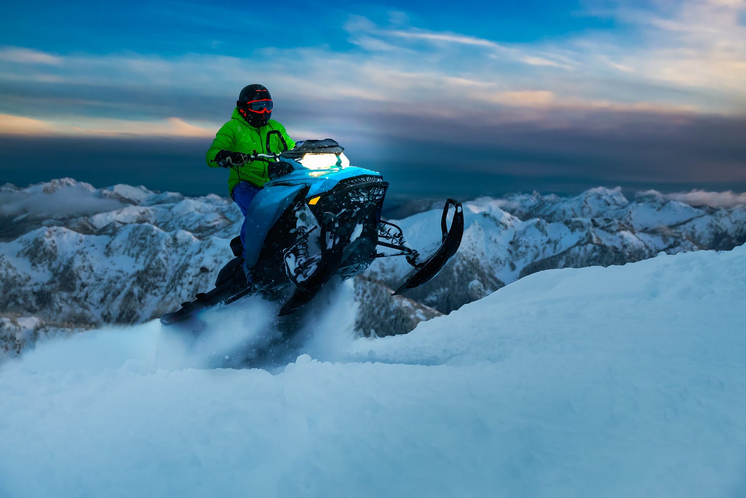 a snowmobile popping a wheelie on the top of a mountain.