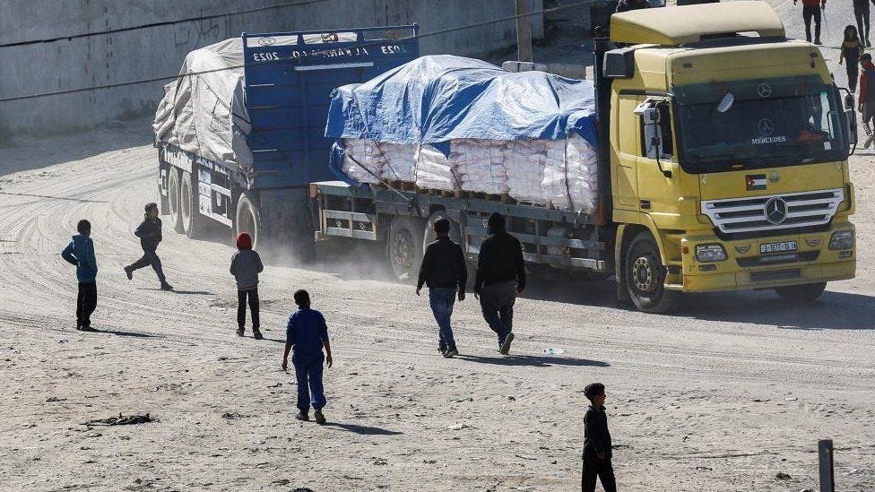 People standing near a truck carrying aid in Rafah
