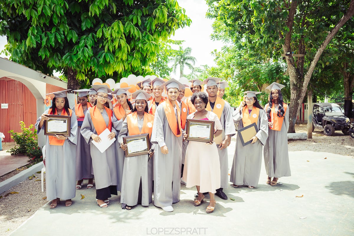 Photo of our graduating class of seniors in their light gray caps and gowns with the signature Dominican Joe orange sashes.