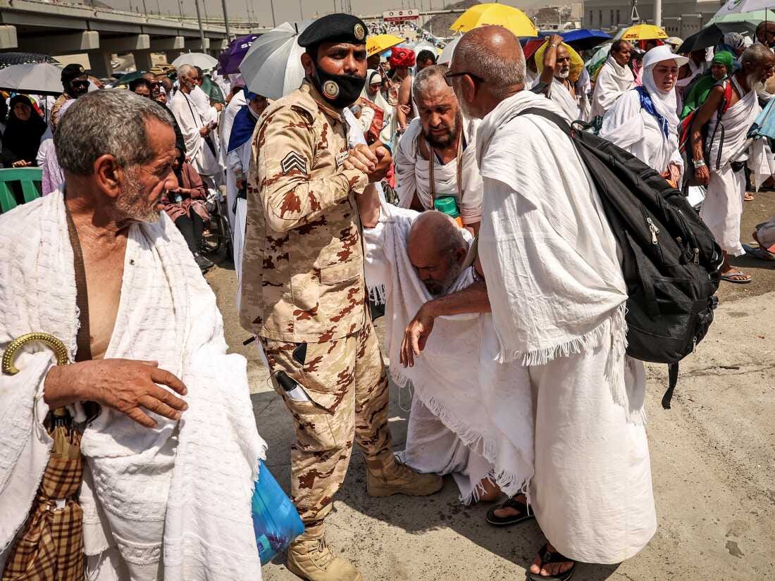 A man affected by the scorching heat is helped by another Muslim pilgrim and a police officer during the Hajj pilgrimage in Mina on June 16.