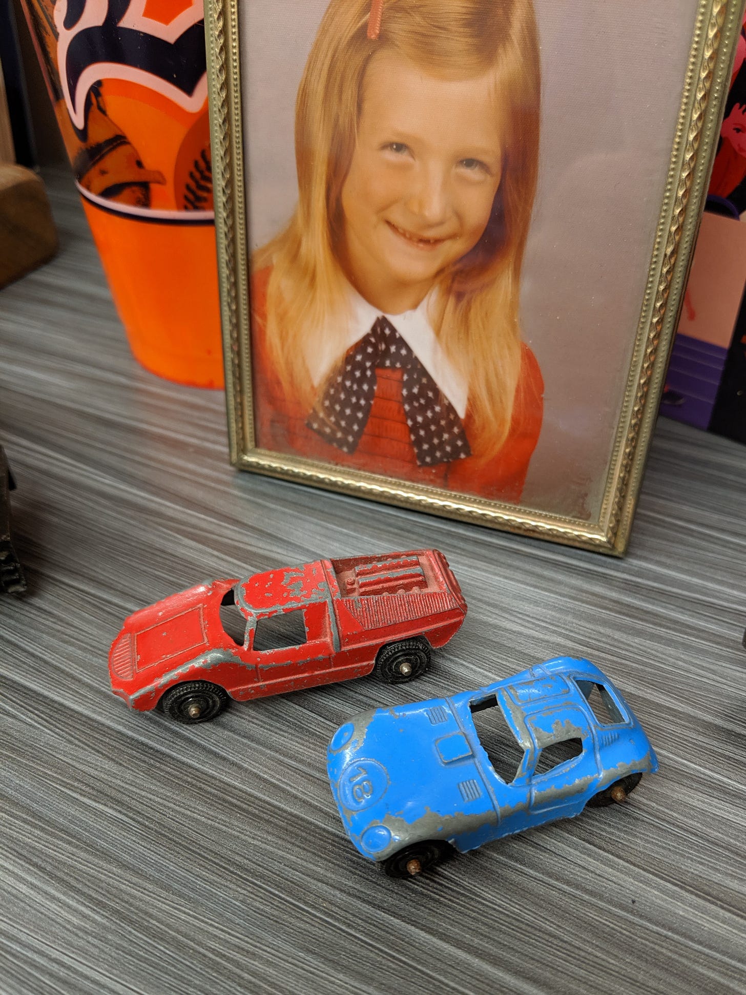 a photo of me as a small child, dressed in a patriotic red, white, and blue, plus a red and a blue toy car