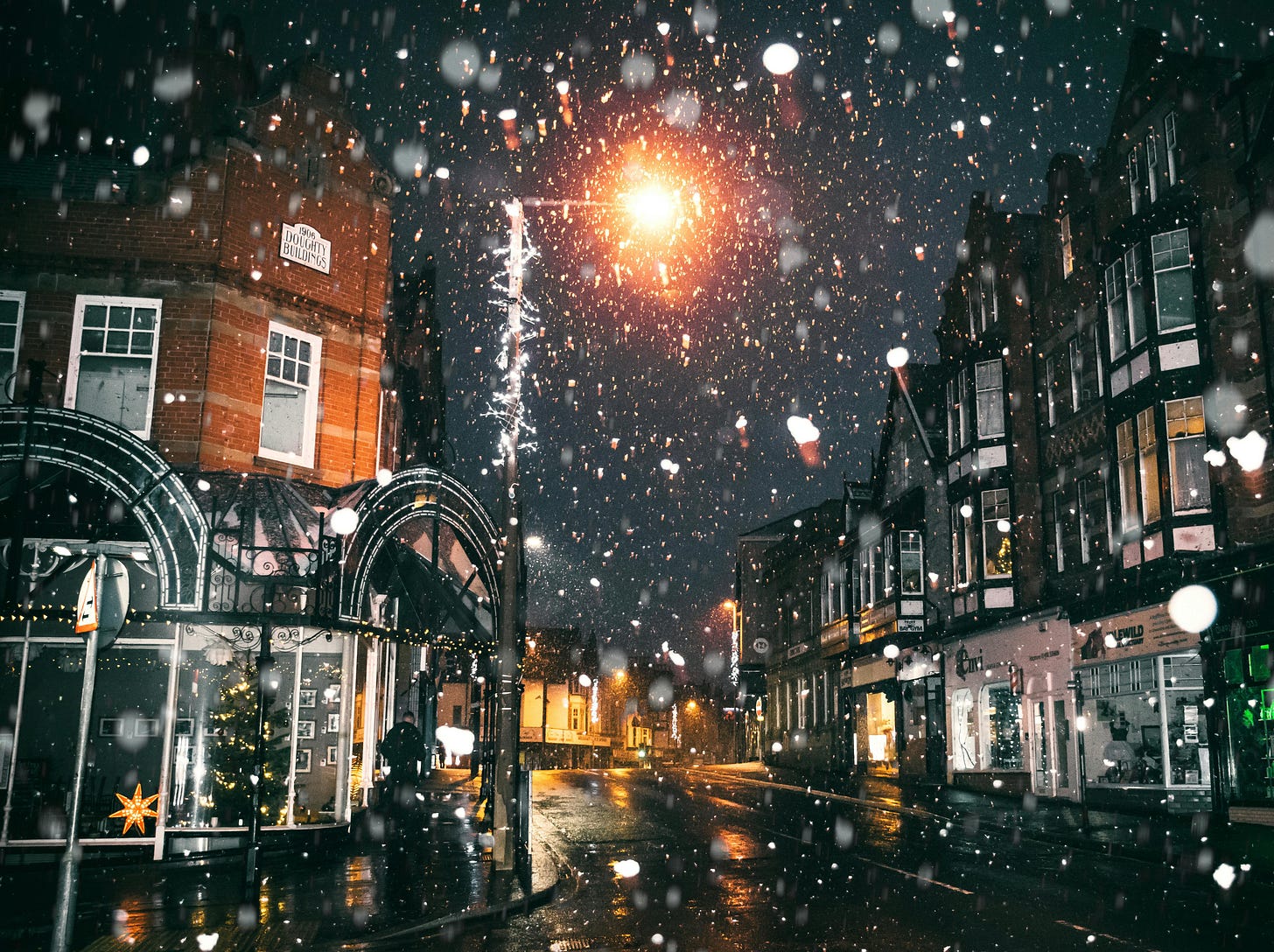 dark snowy night in a small town with christmas lights in the windows