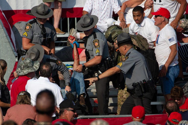 Police officers rushing to remove Comperatore from the stands after the shooting. AFP via Getty Images