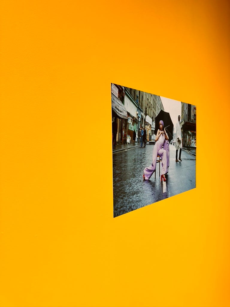 Photo of a fashionable 1970's young Black woman mounted on a bright sunflower yellow wall.