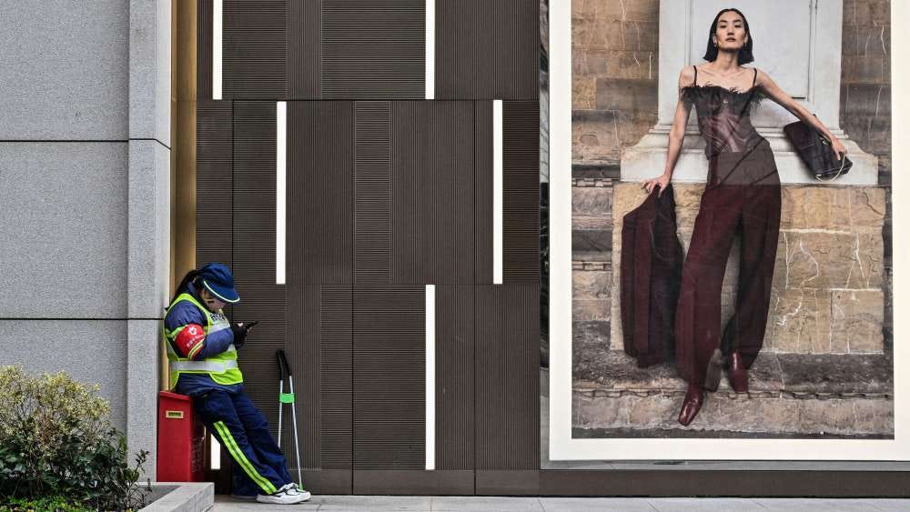 A worker stands next to a shopping mall in Shanghai.