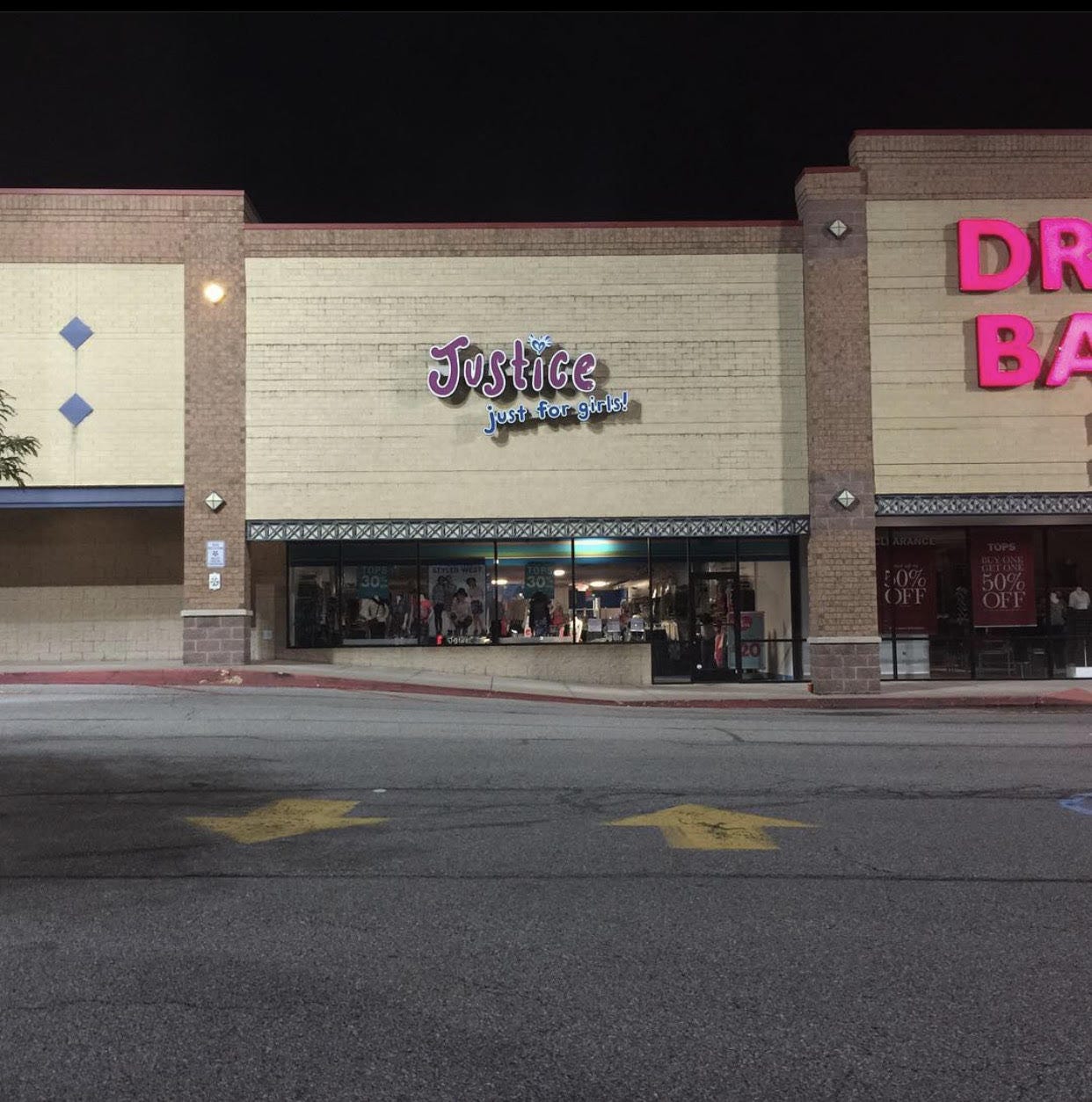 A storefront that is called "Justice" with a phrase underneath reading "just for girls." The picture shows the store with its lights off.