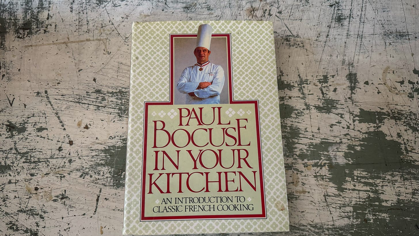 A copy of "Paul Bocuse in Your Kitchen" The subtitle is "An Introduction to Classic French Cooking"