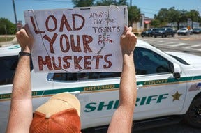 A man in Titusville, FL, holds a sign that reads, 'Load Your Muskets,' as he shows his support for former President Donald Trump last week.