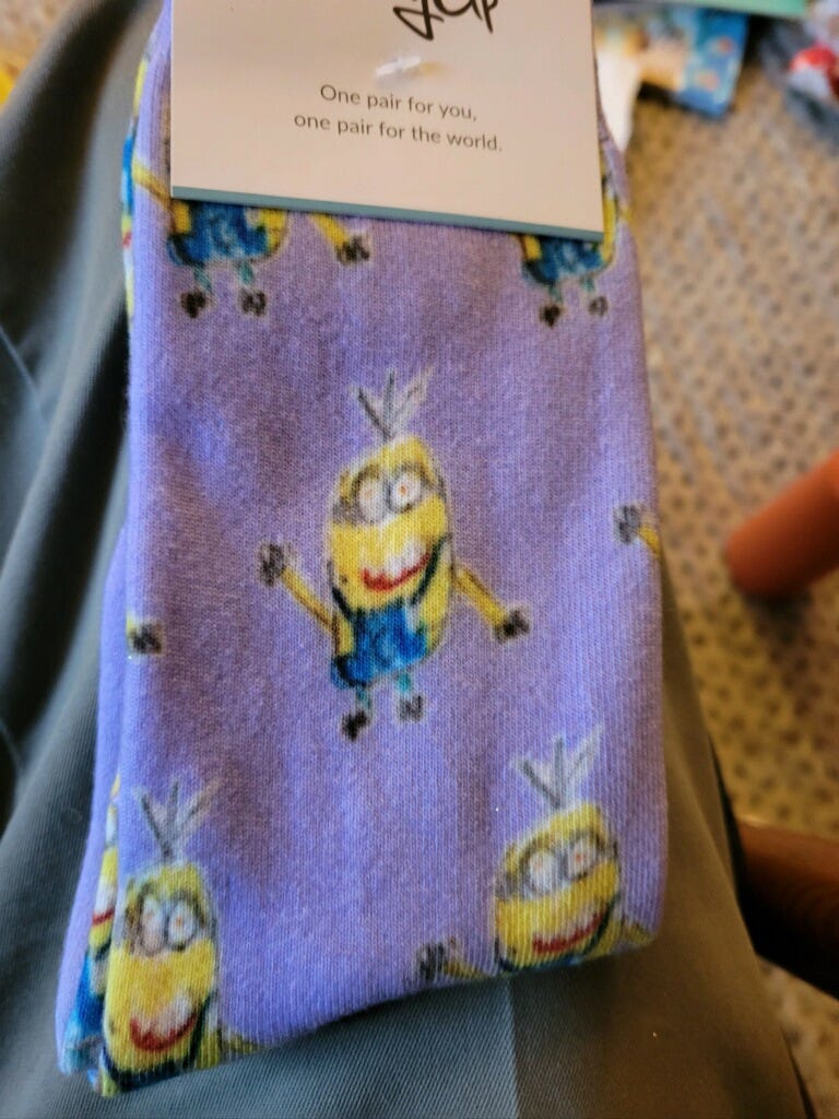 A photo of a pair of purple socks with hand-drawn minions on them.