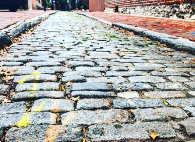 An image of a cobblestone street lined with brick sidewalks.