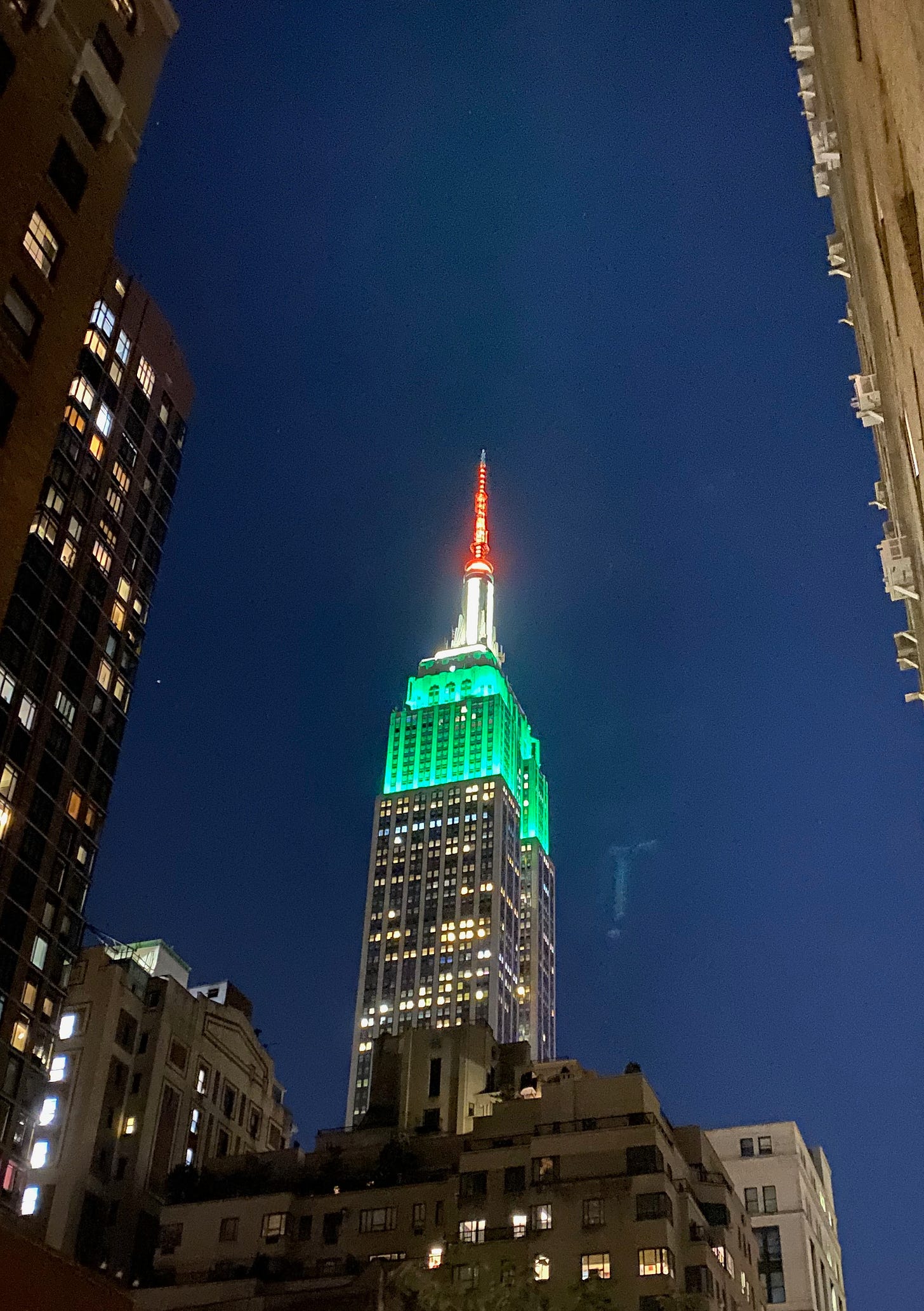 The Empire State Building lit up in orange, white and green.
