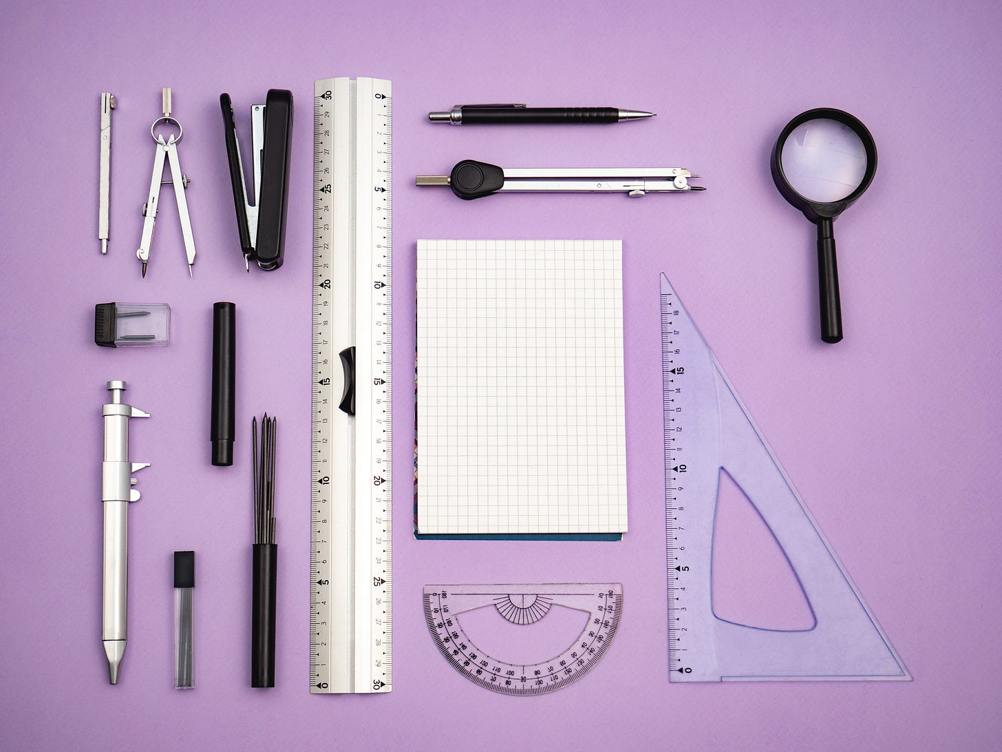 Photo of office tools flay layed on purple background.