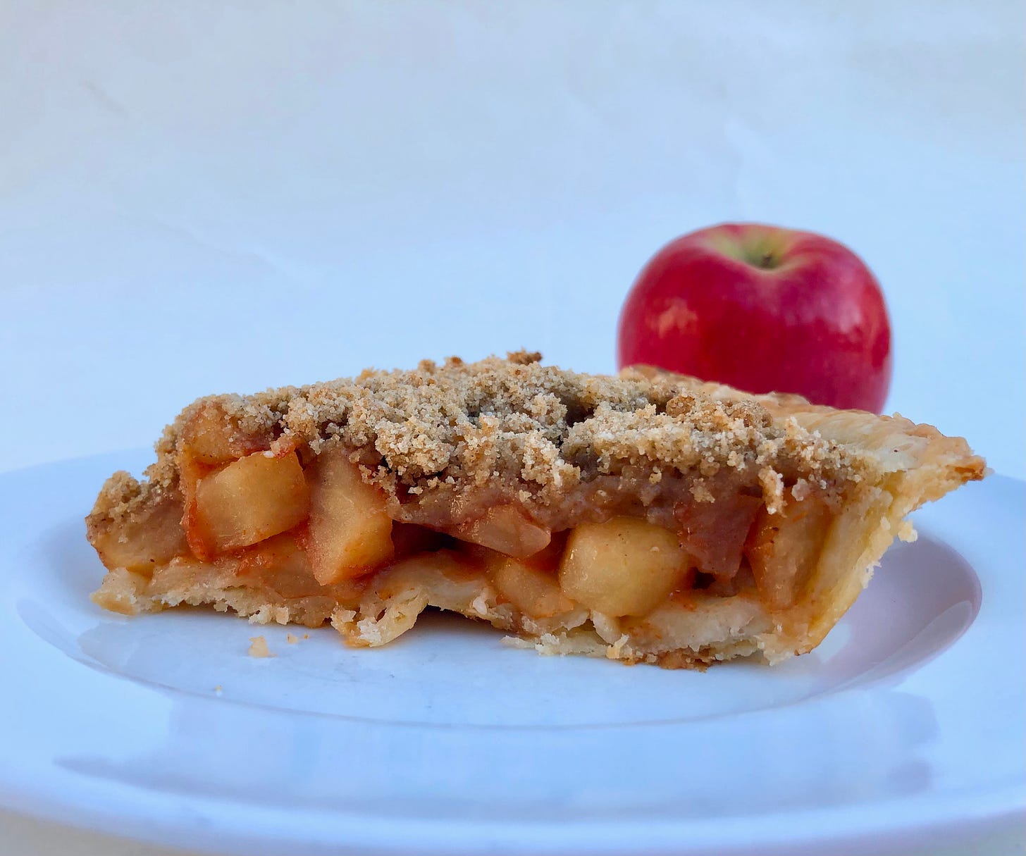 a slice of apple ketchup pie with a fresh apple in the background