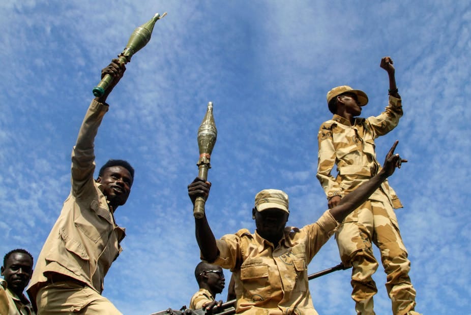 Two men holding hand grenades while another holds up a clenched fist