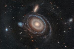 LEDA 1313424, aptly nicknamed the Bullseye, is two and a half times the size of our Milky Way and has nine rings — six more than any other known galaxy. High-resolution imagery from NASA’s Hubble Space Telescope confirmed eight rings, and data from the W. M. Keck Observatory in Hawaii confirmed a ninth. Hubble and Keck also confirmed which galaxy dove through the Bullseye, creating these rings: the blue dwarf galaxy that sits to its immediate center-left.