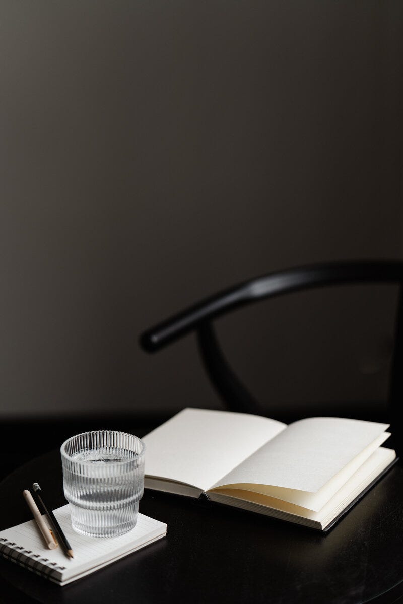 books open on a black table,  next to a glass of water