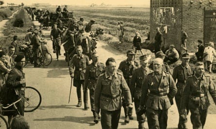 Old postcard of people watching German soldiers walking on a road in Holland in 1945 that was captioned ‘Departure of the Herrenvolk [master race]’