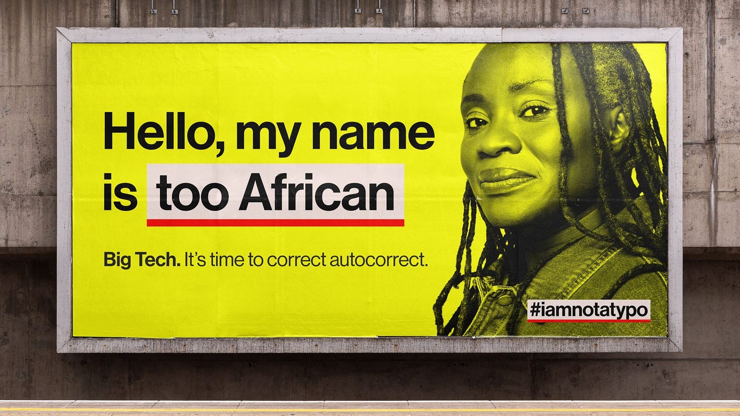 Un cartellone della campagna I Am Not a Typo. Su sfondo giallo un testo dice “Hello, my name is too African”. Le parole too African sono evidenziate in bianco e sottolineate in rosso. Sotto, un’altra scritta "Big Tech. It’s time to correct autocorrect.” A destra l’immagine di una donna afrodiscendente con lunghi capelli dreadlock che sorride all’obiettivo.