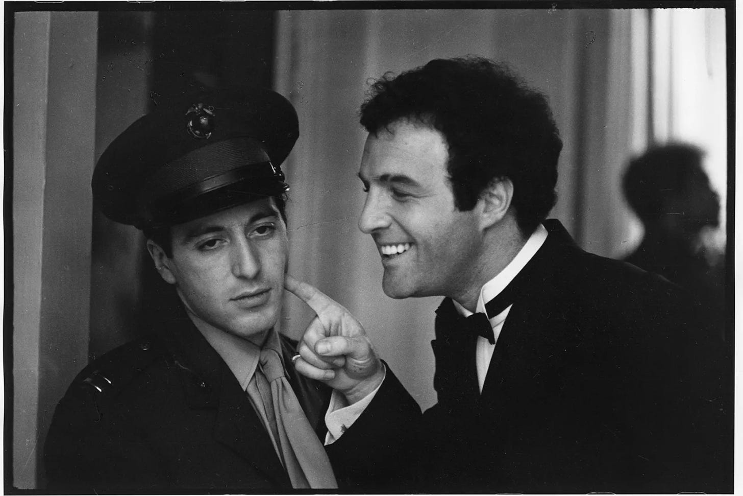 Sonny Corleone apontando o dedo para a bochecha de Michael Corleone de um jeito debochado, enquanto ele faz cara de irritado