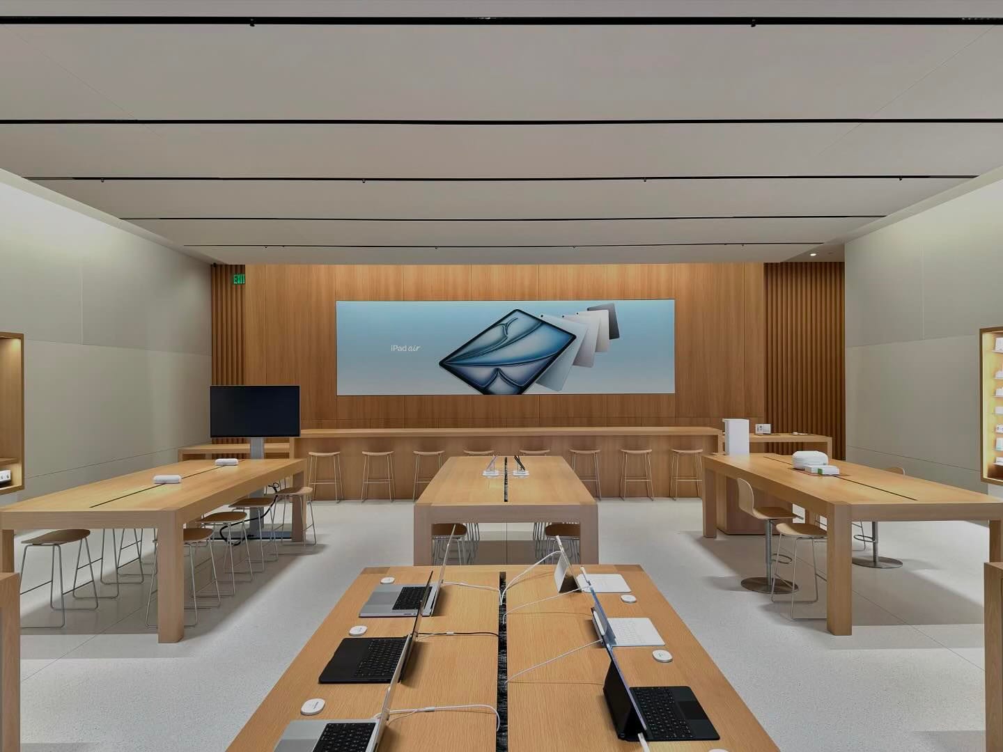 The interior of Apple Bridge Street. The back wall is wood, and in the center is a large graphic panel. A Genius Bar runs the width of the store.