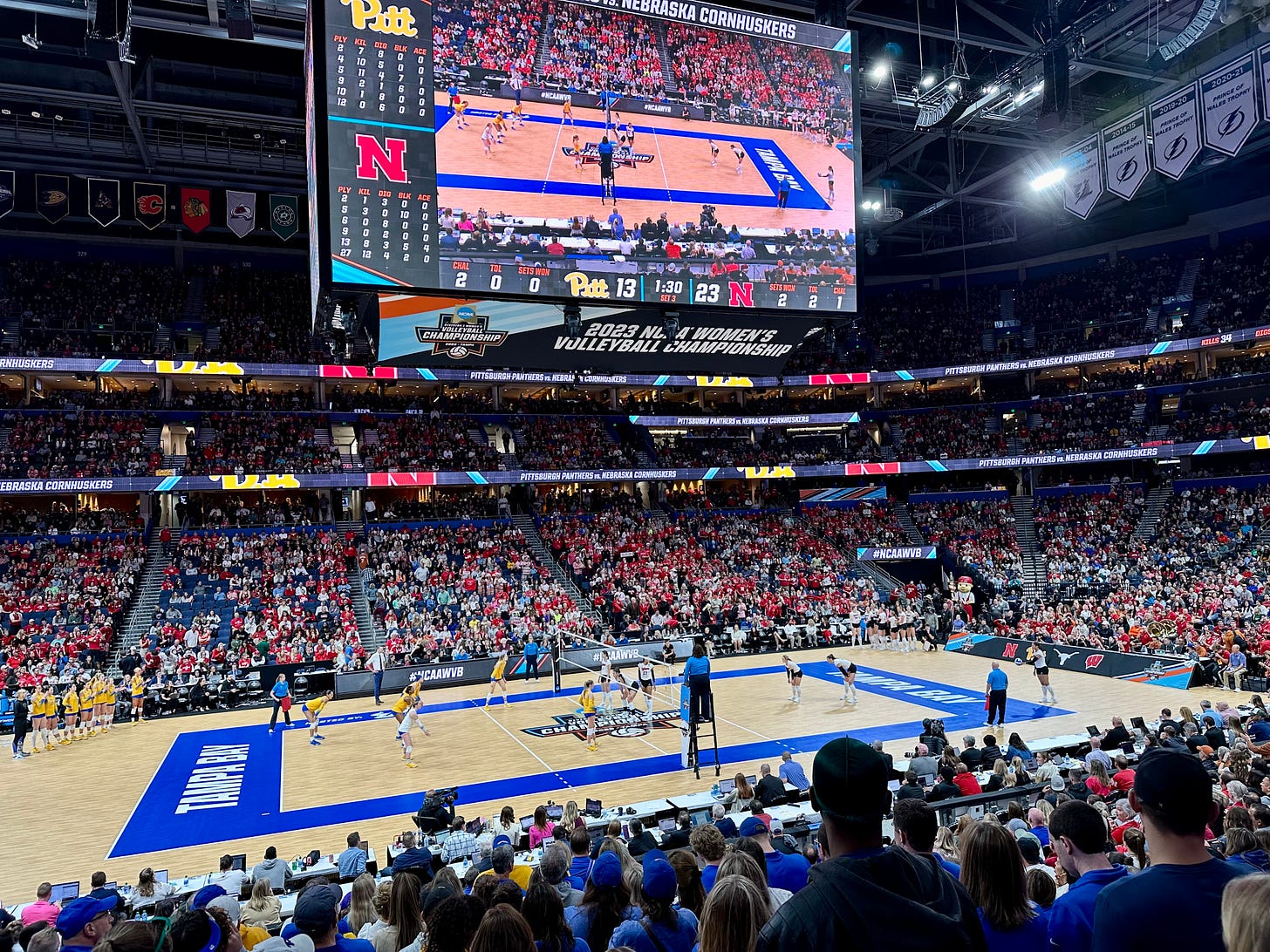 A photograph of Tampa's Amalie Arena during the 2023 NCAA Volleyball Championships shows many more Nebraska fans in red than other fans