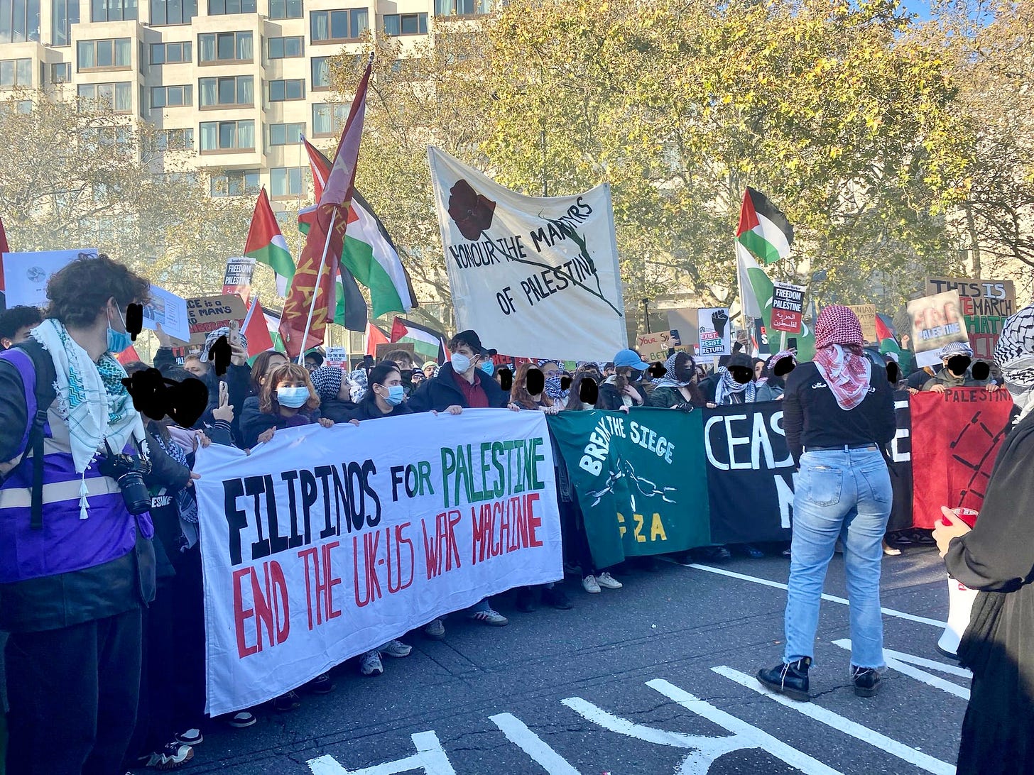Photo of protestors at a Palestine demonstration, the banner at the front reads: FILIPINOS FOR PALESTINE END THE U.K.-US WAR MACHINE