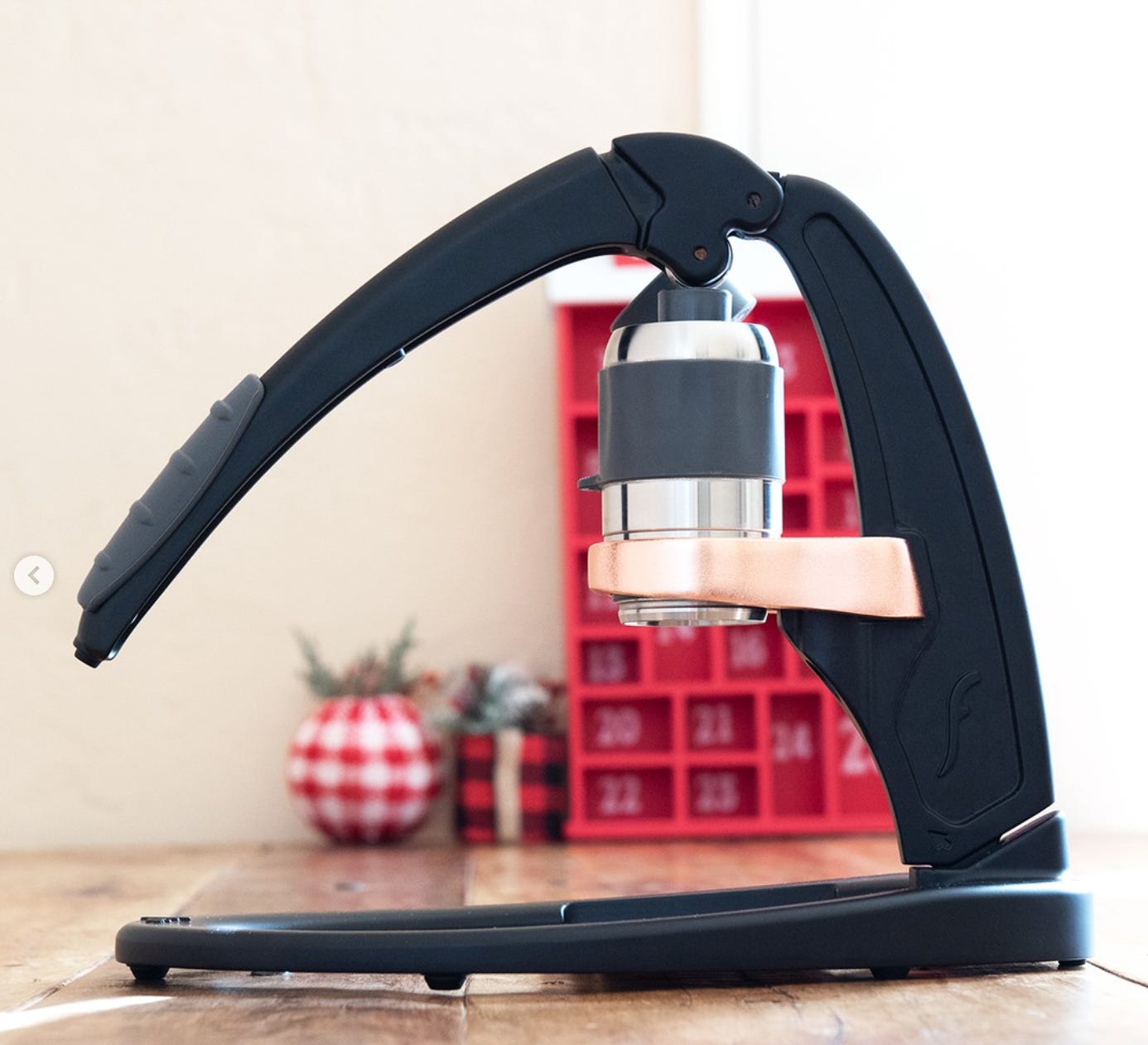 Side view of a modern style lever handle manual espresso machine in black finish with a bronze portafilter basket.