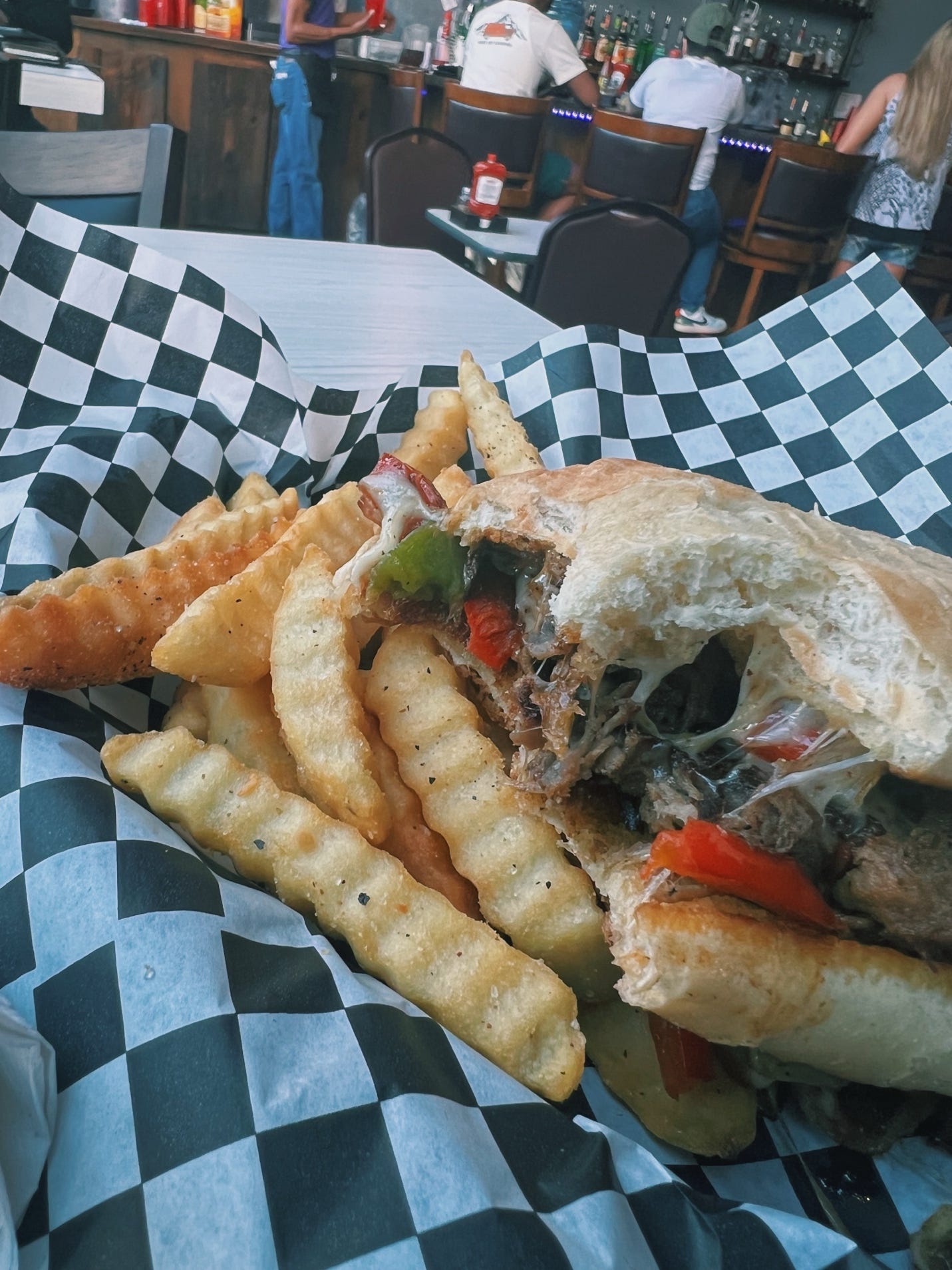 A sandwich and fries on a checkered paper

AI-generated content may be incorrect.