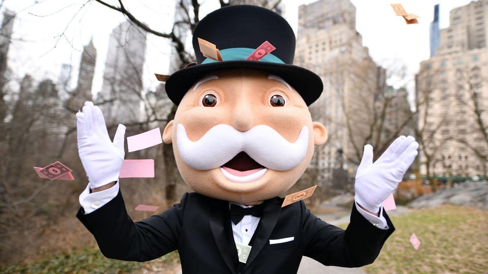 An actor dressed as the Mr. Monopoly mascot surrounded by a flurry of game cards, in New York's Central Park