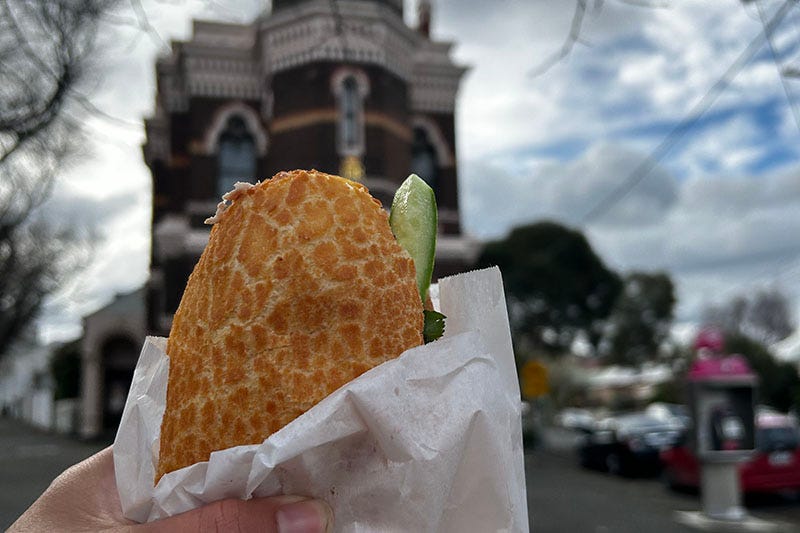 A hand holds a bahni mi roll in front of an ornate post office.