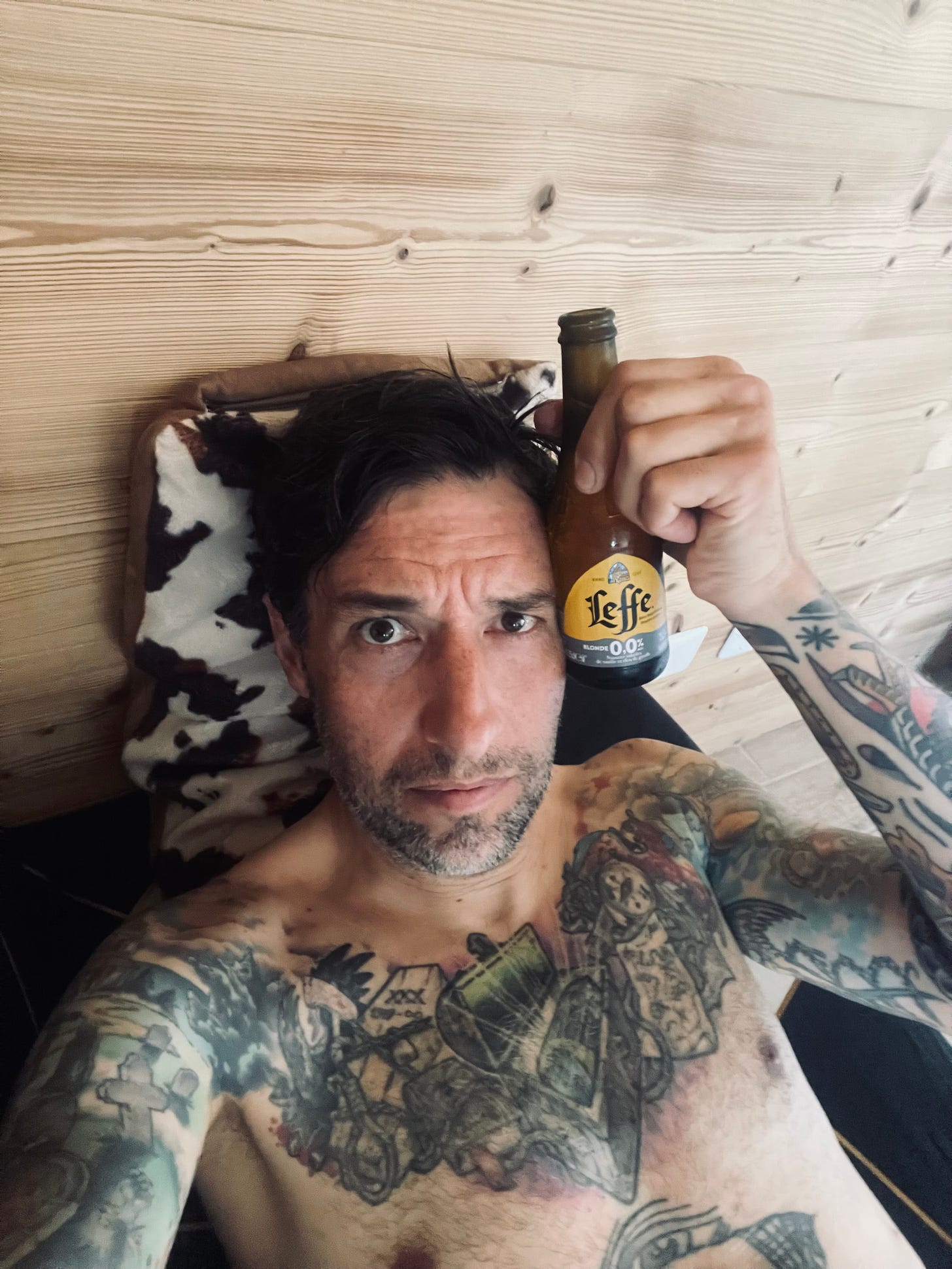 The author lying on a couch holding an alcohol free beer to his head