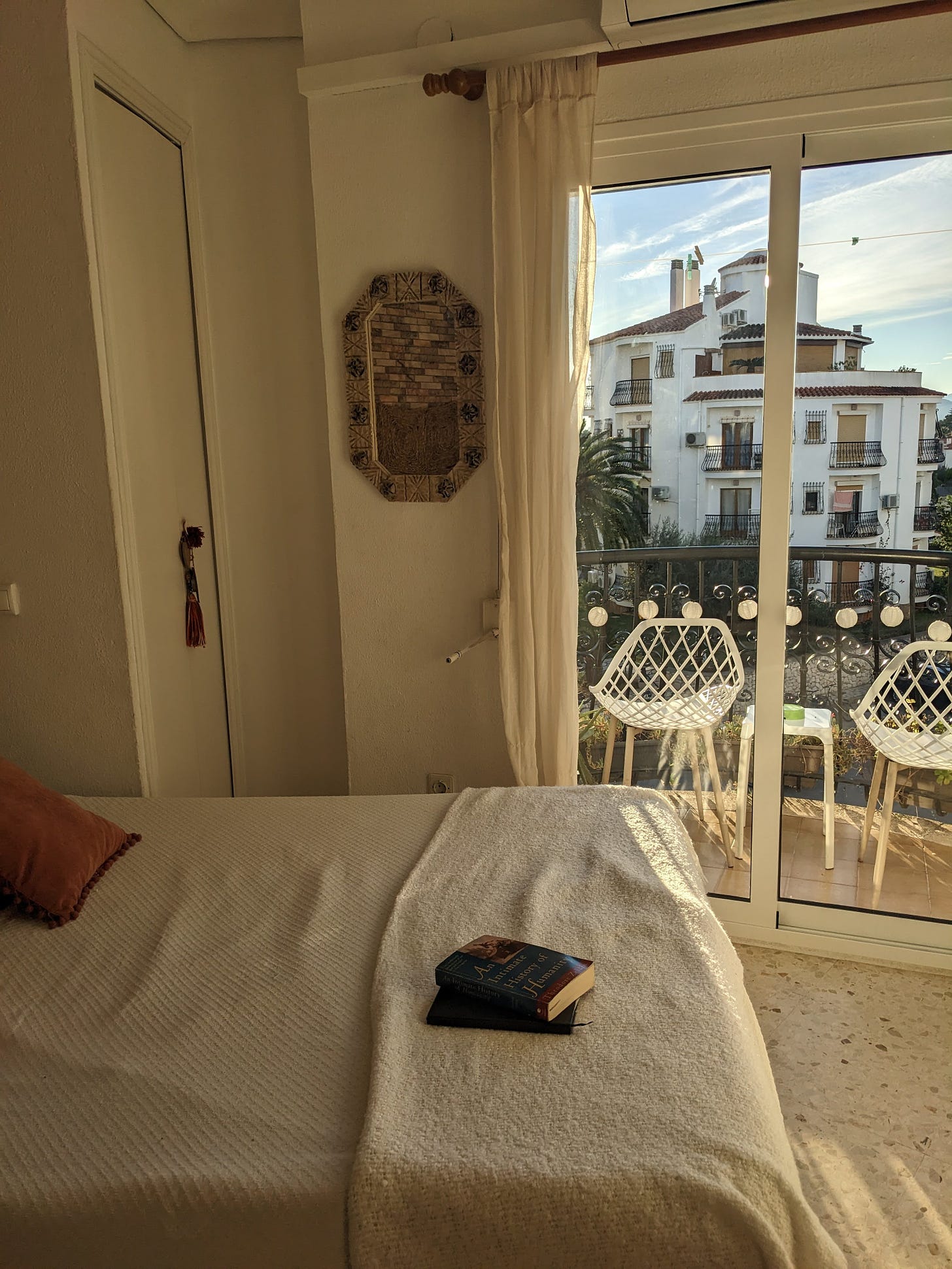 photo of a bed with a white bedspread, and a glass door to a balcony.