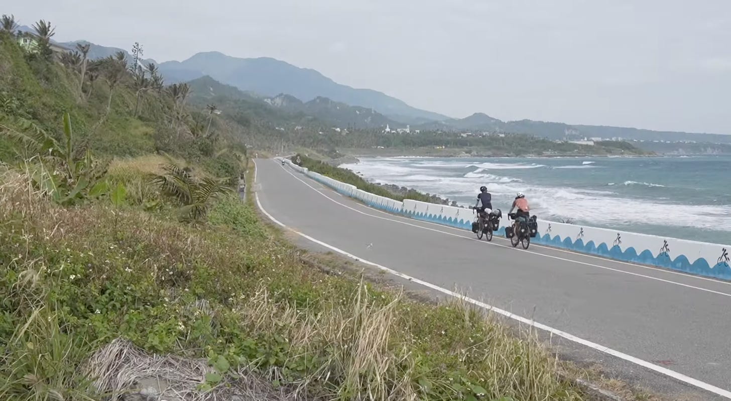 Deux cyclistes le long d'une route le long de la mer a Taiwan.