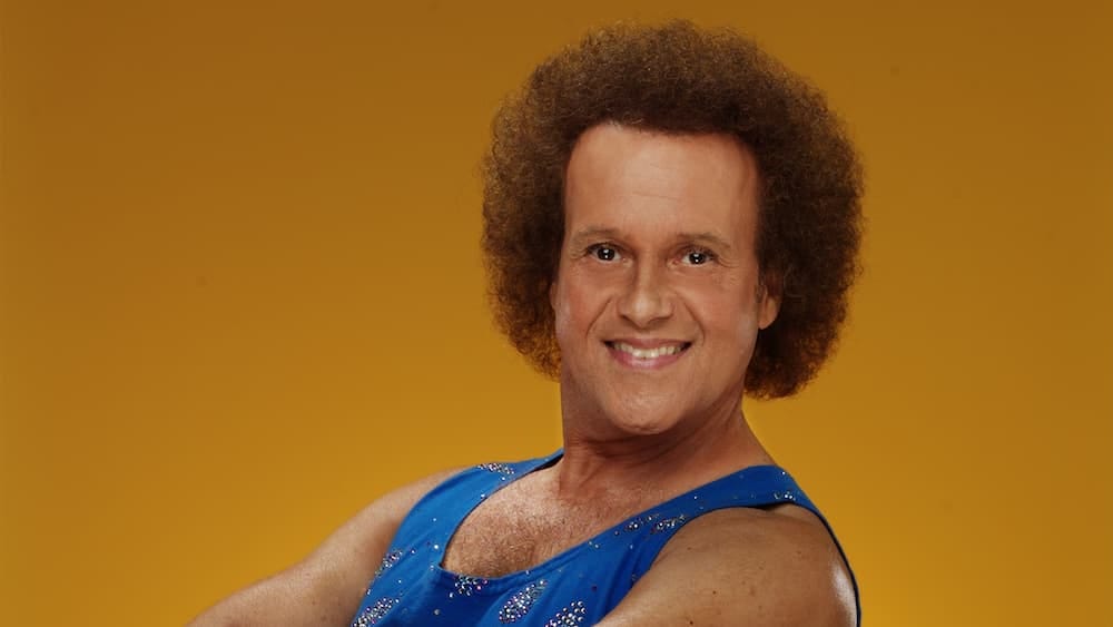 Richard Simmons in a blue outfit against a gold background