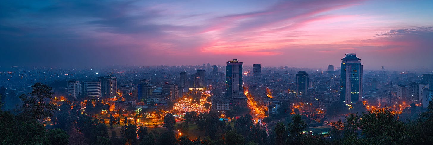 The image shows a vibrant cityscape at dusk, with a sky glowing in pink and blue tones. Tall buildings with lit windows rise above the bustling streets below, filled with glowing lights from traffic. Trees in the foreground add a natural element, contrasting with the urban setting. The scene captures the city's transition from day to night, blending calm and lively atmospheres.