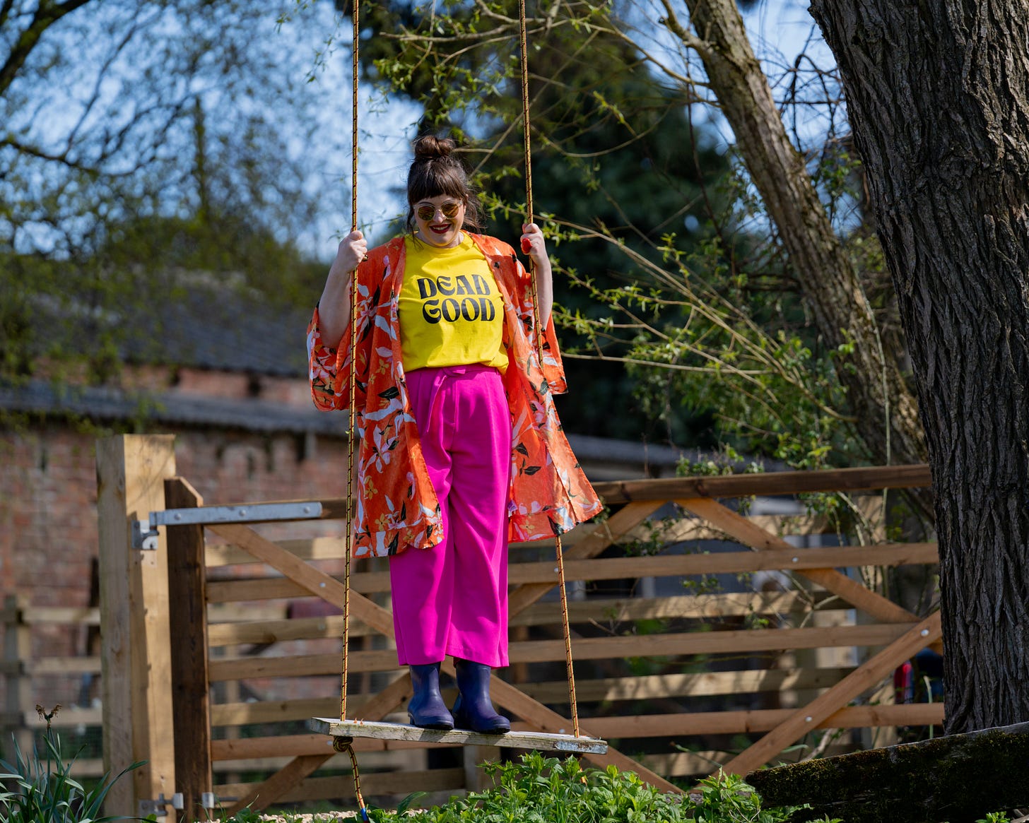 White woman in bright clashing colours standing up on a swing