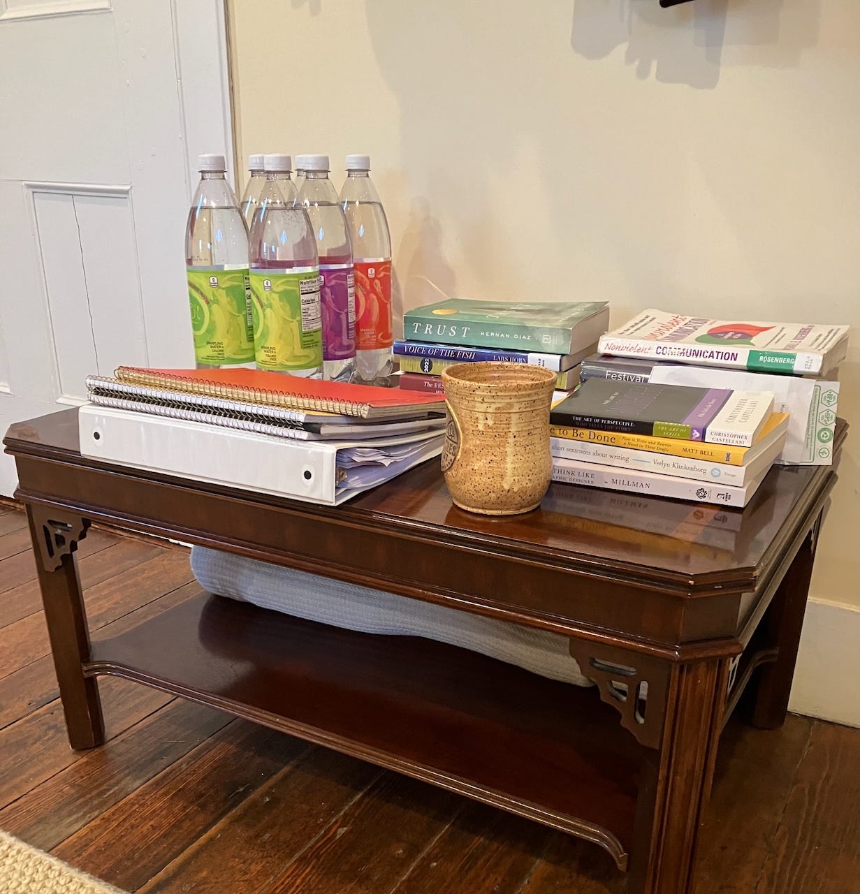 wood table covered in books and seltzer and notebooks