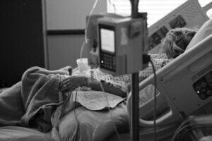 Hospital patient in bed behind machines. Pixabay