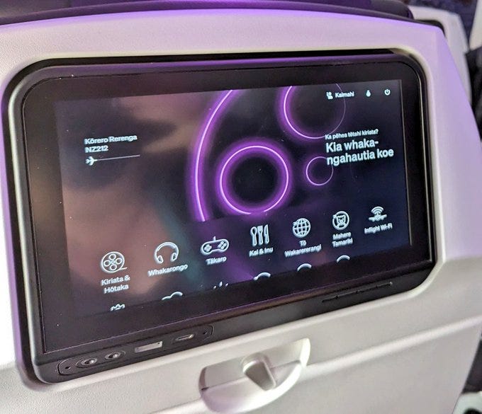 The screen on the back of an airplane seat with widgets displaying in Te Reo Māori. In large letters: Kia whaka-ngahautia koe 