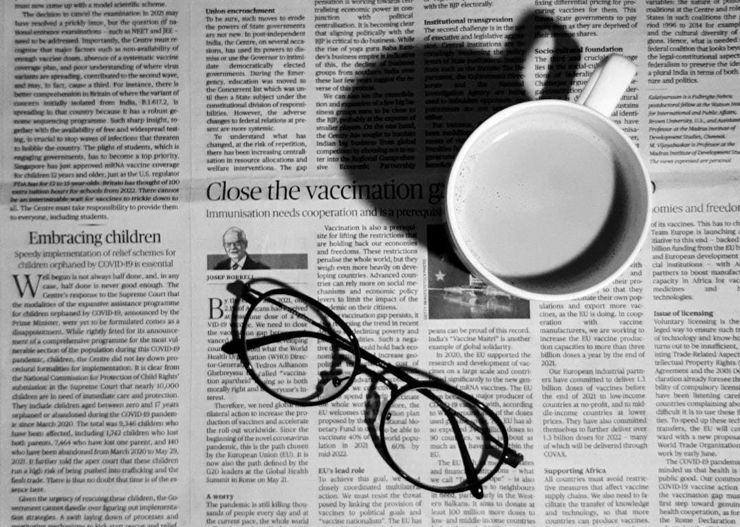 a cup of coffee and a pair of glasses on a newspaper
