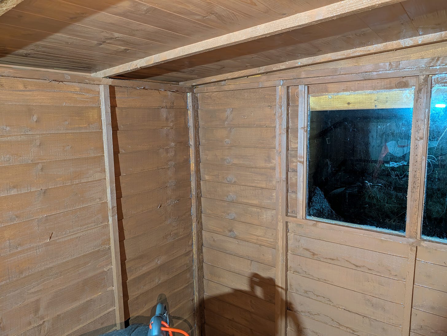Shed wall with wet, dark brown paint, resembling melted chocolate.