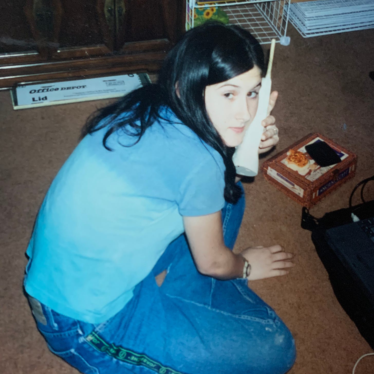 Teenage Lyric is in a blue shirt and blue jeans, scowling at someone who is taking their picture from behind as they talk on the phone. 