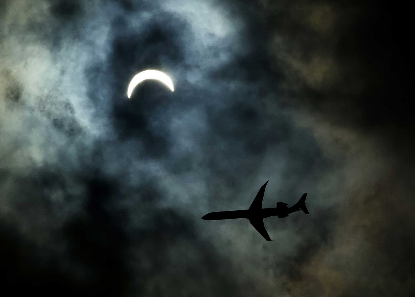 A commercial plane flies just beneath a partial solar eclipse A commercial plane flies just beneath a partial solar eclipse