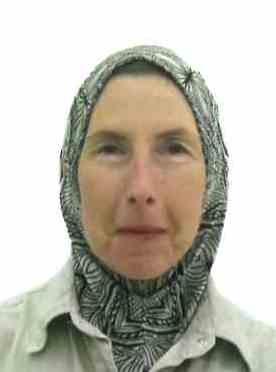 Slightly smiling woman in passport photo wearing black and white instant hijab.