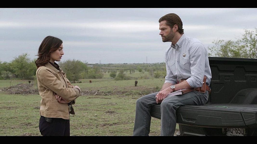 Walker Cassie talking to Jared Padalecki sitting on back of truck looking stern and vexed.