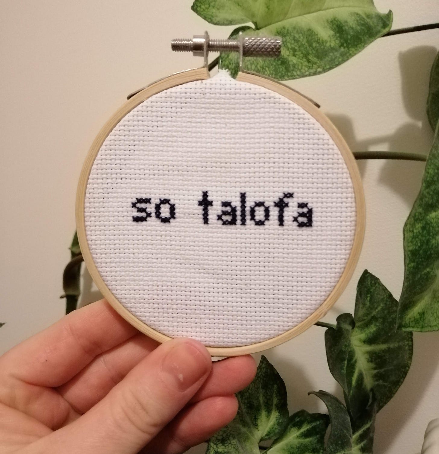 Cross stitch in a small frame being held in someone's hand. The text simply says "so talofa"