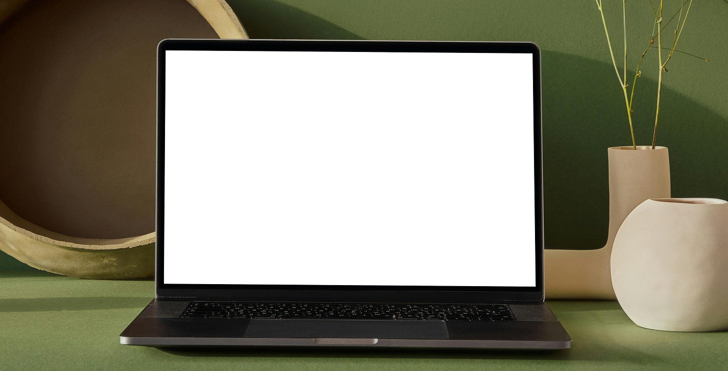 A laptop with a white screen sits open in front of a green backdrop.