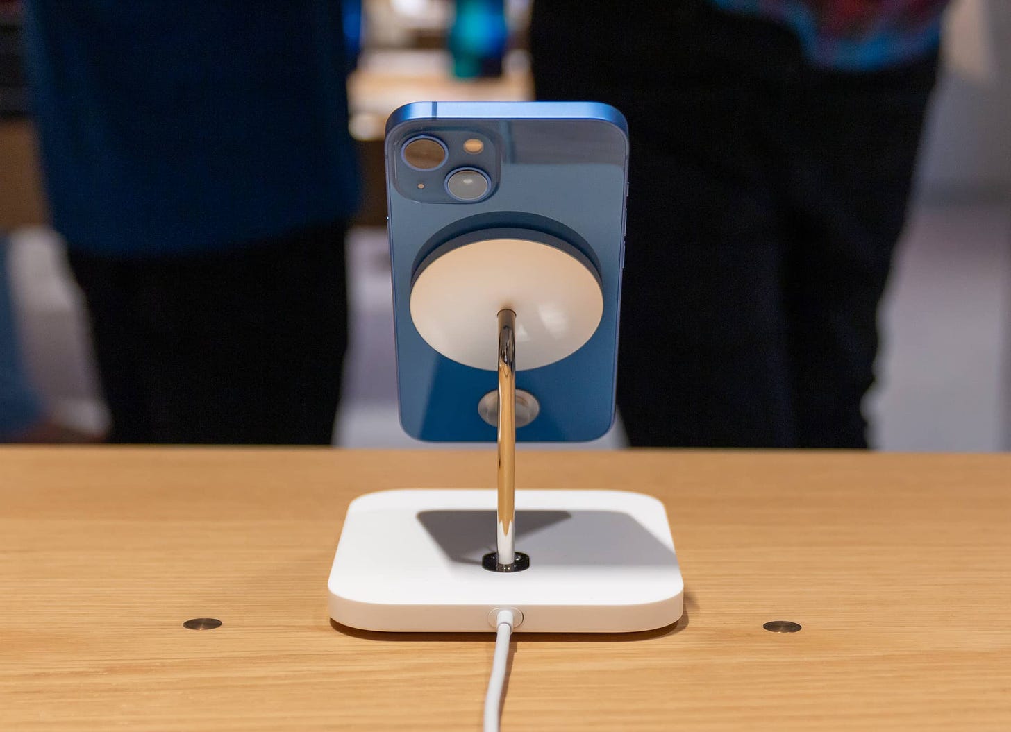 A MagSafe dock charging an iPhone 13 mini at an Apple Store.