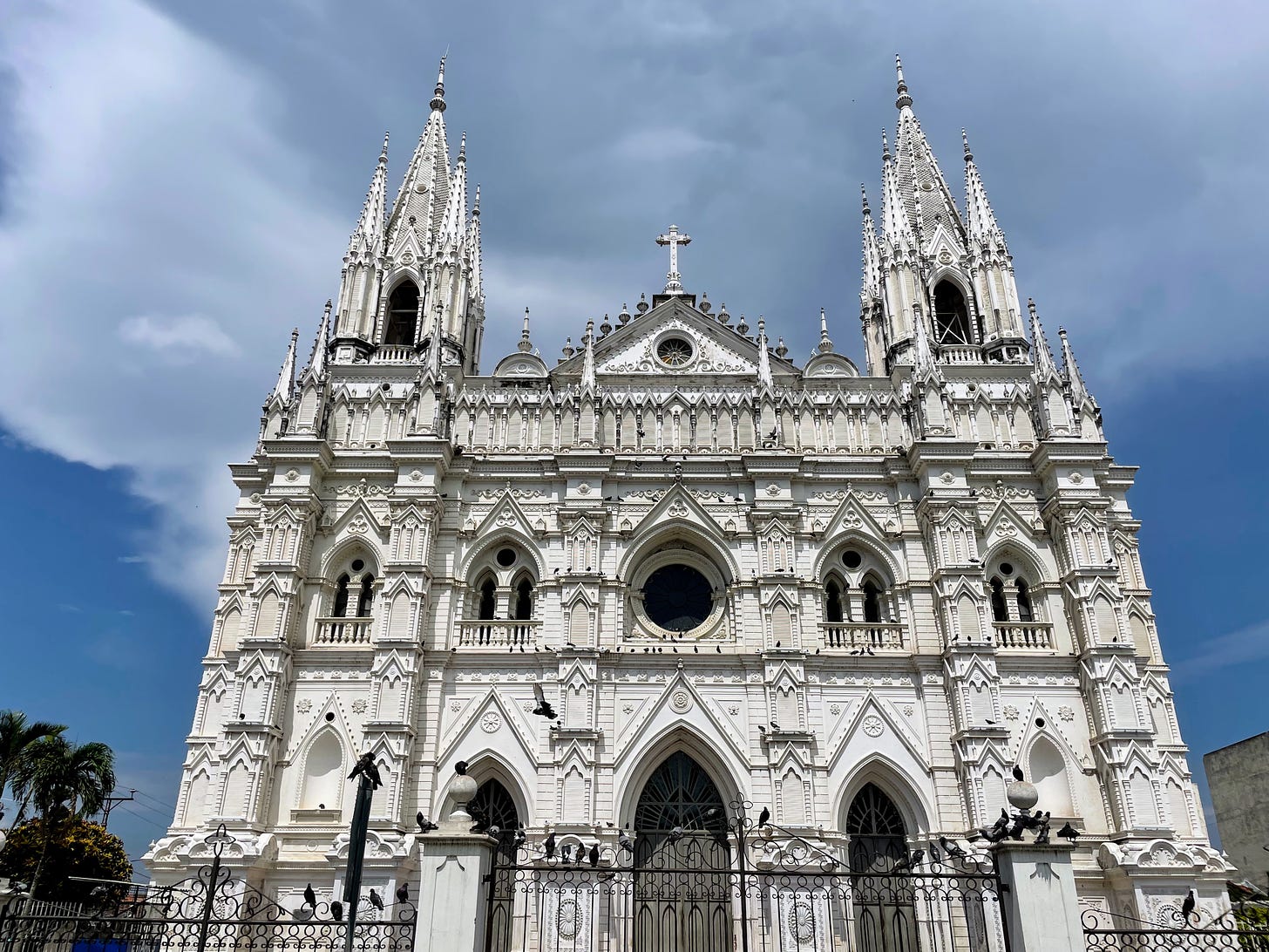 A large, ornate white cathedral stands against a blue sky