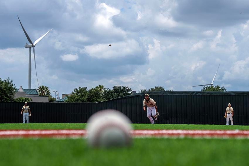 Lyford, TX - May 17, 2023: Members of the Lyford high-school baseball team practice of a new athletic field partially funded by wind turbine tax bonds in Lyford, TX. Industrial energy-producing wind turbines cover hundreds of acres of farmland in Lyford, TX. (Photo by Ben Lowy for The Texas Tribune)